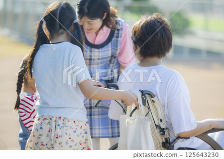 Young Carer: Primary school student pushing a wheelchair and a caregiver Young Carer: Primary school student pushing a wheelchair and a caregiver 125643230