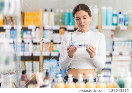 Female buyer buys medicinal ointment at pharmacy Female buyer buys medicinal ointment at pharmacy 125643315