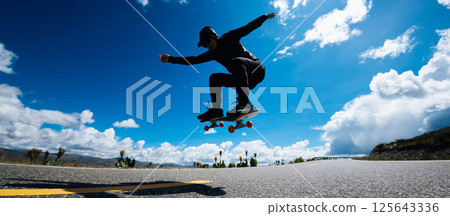 Skateboarder skateboarding on country road Skateboarder skateboarding on country road 125643336