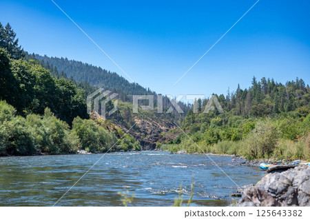 Wild and scenic Rogue River in Southern Oregon with a distant rafter floating. Wild and scenic Rogue River in Southern Oregon with a distant rafter floating. 125643382