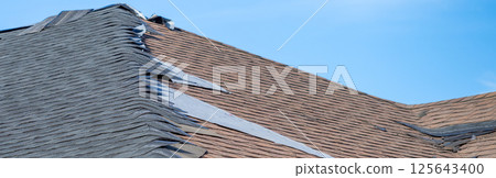 ground level view re-roofing overlay project at a residential house where new shingles are placed on top of existing tiles.  125643400