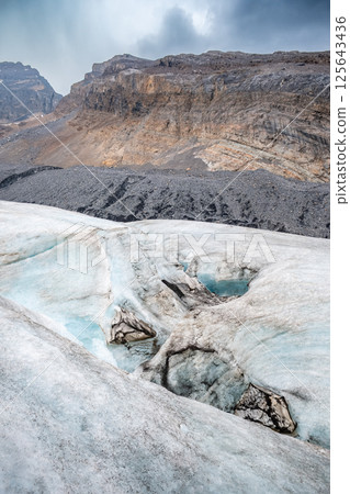 Crevasse in the ice from melting at Athabasca Glacier in Jasper National Park with cloudy sky 125643436