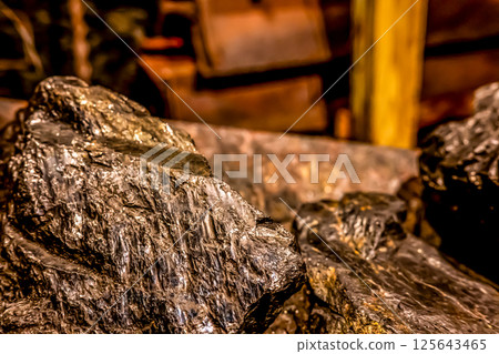 Selective focus on anthracite coal on a conveyer belt with defocused group in the Lackawanna Coal Mine Tour at McDade Park. Selective focus on anthracite coal on a conveyer belt with defocused group in the Lackawanna Coal Mine Tour at McDade Park. 125643465