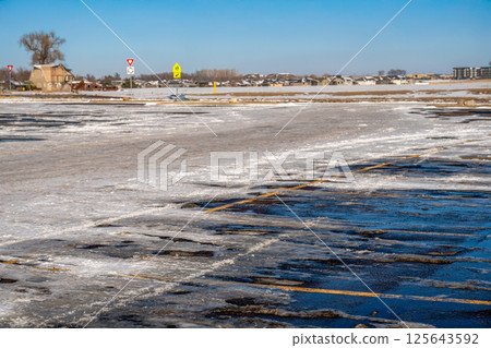 Snow covered parking lot with the lines covered in some locations. 125643592