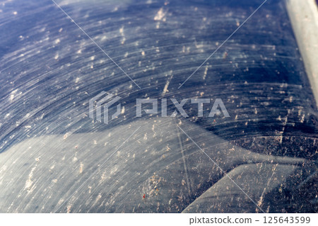 Smeared and dirty front windshield of a vehicle after hitting bugs. 125643599