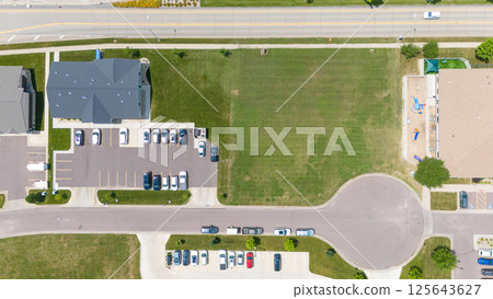 Drone aerial view of an open lot of undeveloped land between two businesses.  125643627