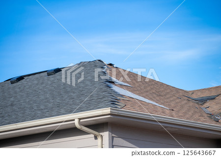 ground level view re-roofing overlay project at a residential house where new shingles are placed on top of existing tiles. ground level view re-roofing overlay project at a residential house where new shingles are placed on top of existing tiles. 125643667