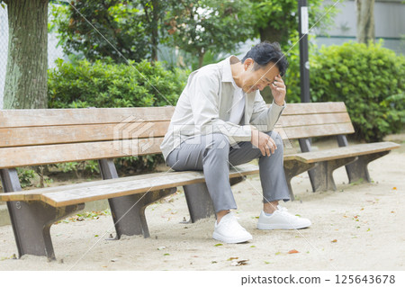 Middle-aged man feeling down on a park bench Middle-aged man feeling down on a park bench 125643678