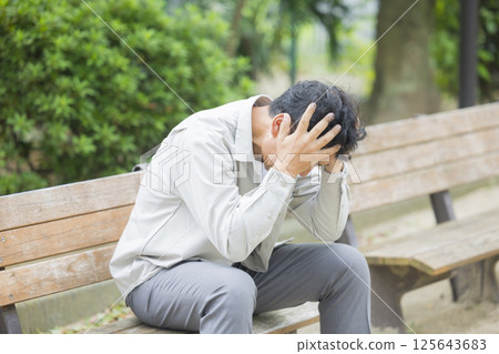 中年男子在公園長椅上心情低落 中年男子在公園長椅上心情低落 125643683