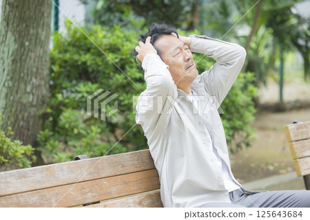 Middle-aged man feeling down on a park bench 125643684