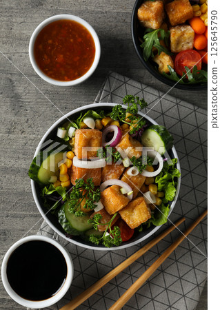Fried tofu salad with sauces on a wooden background Fried tofu salad with sauces on a wooden background 125645790
