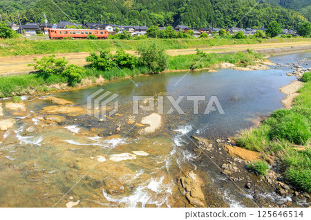 The orange Bantan Line train passing by Nakajibashi Bridge 125646514