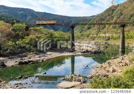 The Yodo Line's famous train crossing the Shimanto River truss bridge 125646569