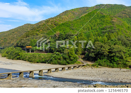 A yellow diesel railcar on the Yodo Line running next to the Hanka Submerged Bridge over the Shimanto River A yellow diesel railcar on the Yodo Line running next to the Hanka Submerged Bridge over the Shimanto River 125646570
