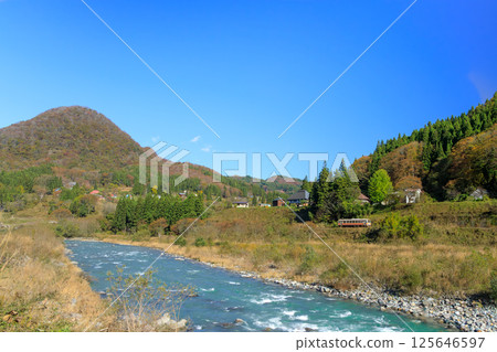 A view of the autumn foliage of Otari Village, Nagano Prefecture, and the Oito Line from the quietly flowing Hime River 125646597
