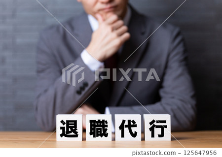 A middle-aged male businessman wearing a suit and worrying about a resignation agent block A middle-aged male businessman wearing a suit and worrying about a resignation agent block 125647956