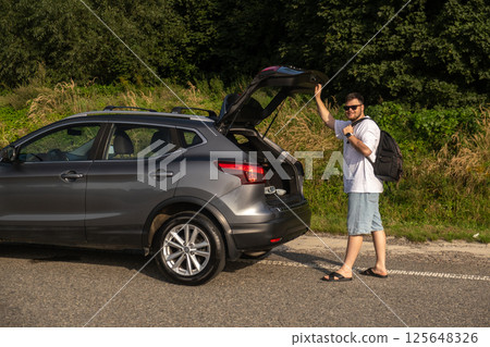 Man with Backpack at Open Car Trunk Man with Backpack at Open Car Trunk 125648326