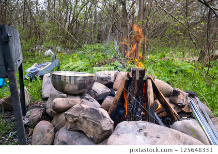 Campfire in Forest with Metal Bowl Nearby 125648331