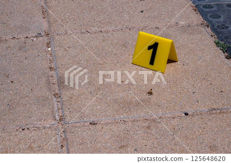 One yellow crime scene marker on the paving slab One yellow crime scene marker on the paving slab 125648620