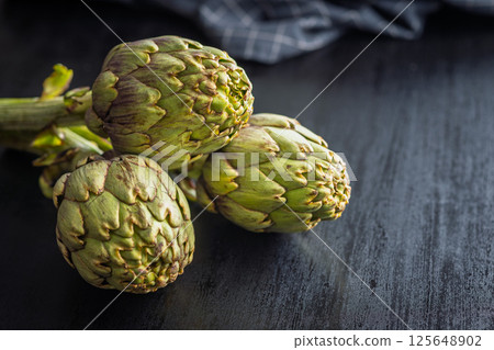 Ripe artichokes plant on black table. 125648902