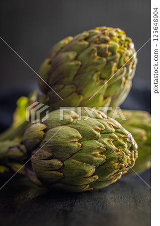 Ripe artichokes plant on black table. Ripe artichokes plant on black table. 125648904