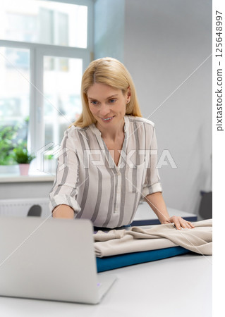 Fashion designer conducting an online workshop in her studio Fashion designer conducting an online workshop in her studio 125648997