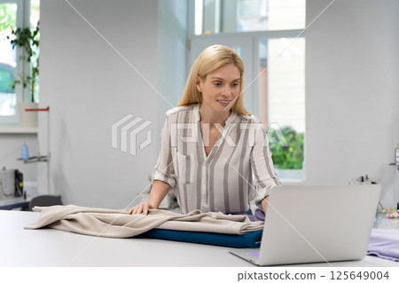 Fashion designer conducting an online workshop in her studio Fashion designer conducting an online workshop in her studio 125649004