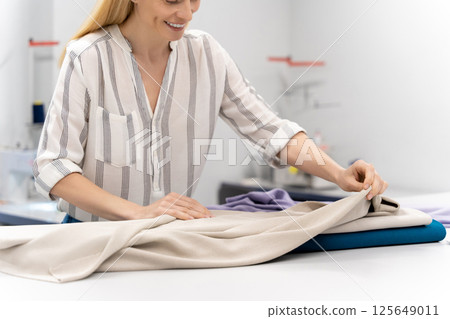 Fashion designer holding fabric in hands while working in design studio 125649011