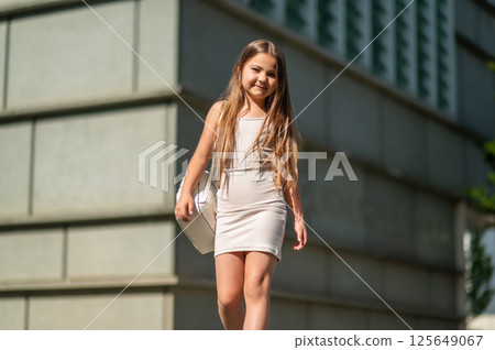 Cute little child walking through the urban street on her way to school carrying backpack Cute little child walking through the urban street on her way to school carrying backpack 125649067