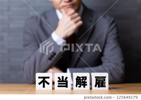 A middle-aged male businessman wearing a suit and worried about unfair dismissal 125649179