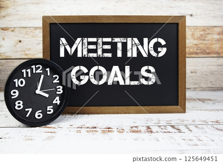 Meeting Goals text message and alarm clock on wooden background Meeting Goals text message and alarm clock on wooden background 125649451