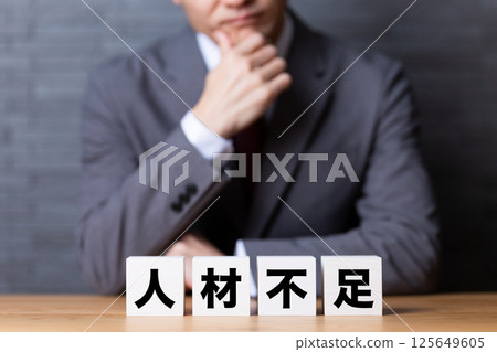 一位穿著西裝的中年男性商人擔心勞動力短缺問題 一位穿著西裝的中年男性商人擔心勞動力短缺問題 125649605