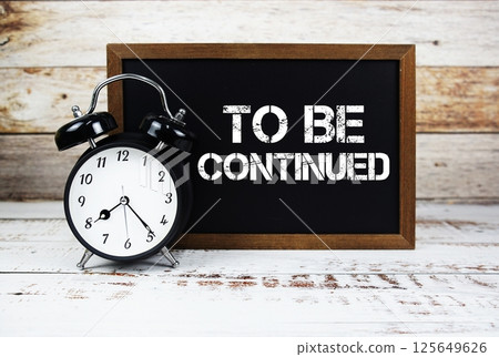 To Be Continued text message and alarm clock on wooden background To Be Continued text message and alarm clock on wooden background 125649626
