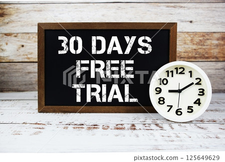 30 Days Free Trial text message and alarm clock on wooden background 125649629