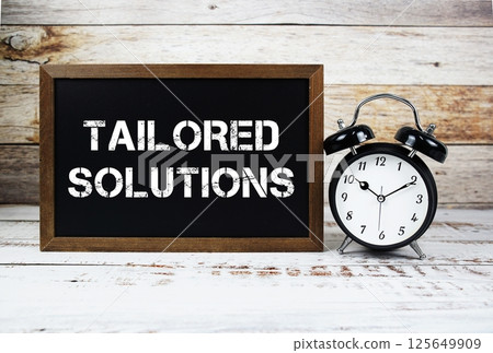 Tailored Solutions text message and alarm clock on wooden background 125649909