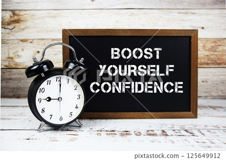 Boost Yourself Confidence text message and alarm clock on wooden background Boost Yourself Confidence text message and alarm clock on wooden background 125649912