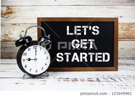 Let's Get Started text message and alarm clock on wooden background 125649962