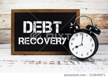 Debt Recovery text message and alarm clock on wooden background Debt Recovery text message and alarm clock on wooden background 125649971