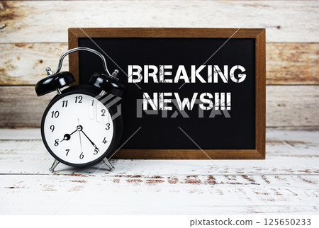 Breaking News!!! text message and alarm clock on wooden background 125650233
