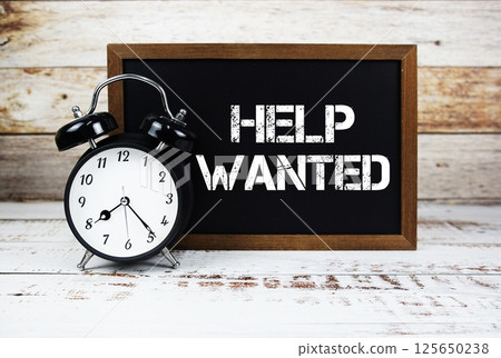 Help Wanted text message and alarm clock on wooden background Help Wanted text message and alarm clock on wooden background 125650238