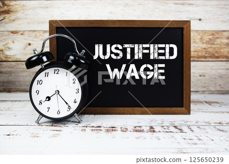 Justified Wage text message and alarm clock on wooden background Justified Wage text message and alarm clock on wooden background 125650239