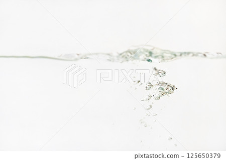 Bubbles in water as its poured into aquarium tank, splashes on surface, white background 125650379