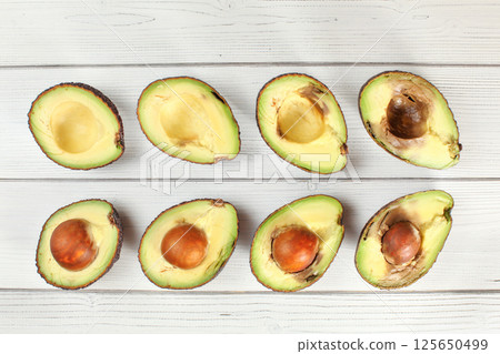 Avocado halves arranged from ripe to over ripen on white boards desk, view from above 125650499