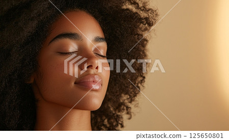 Serene Portrait of a Young Woman with Curly Hair Enjoying Peaceful Moment Against Soft Background 125650801