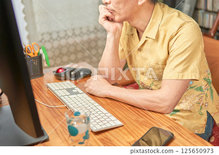 A man thinking deeply while looking at a computer screen 125650973