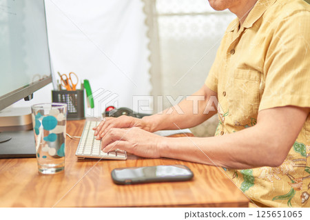 一名男子透過遠距辦公在電腦上工作 一名男子透過遠距辦公在電腦上工作 125651065