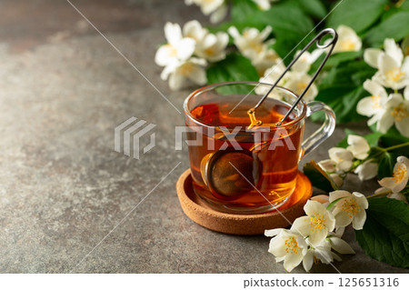 Cup of jasmine tea and fresh jasmine flowers on a stone table. 125651316