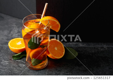 Iced tea or a summer refreshing drink with ice, mint, and orange. 125651317