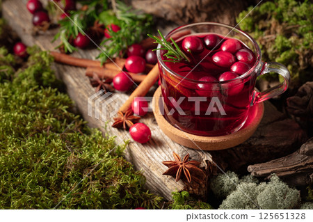 Hot winter drink with cranberries, lime, and rosemary on a old wooden board. 125651328