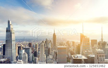 Sunset view of Manhattan skyline bathed in warm golden light and surrounded by glowing skyscrapers 125651462
